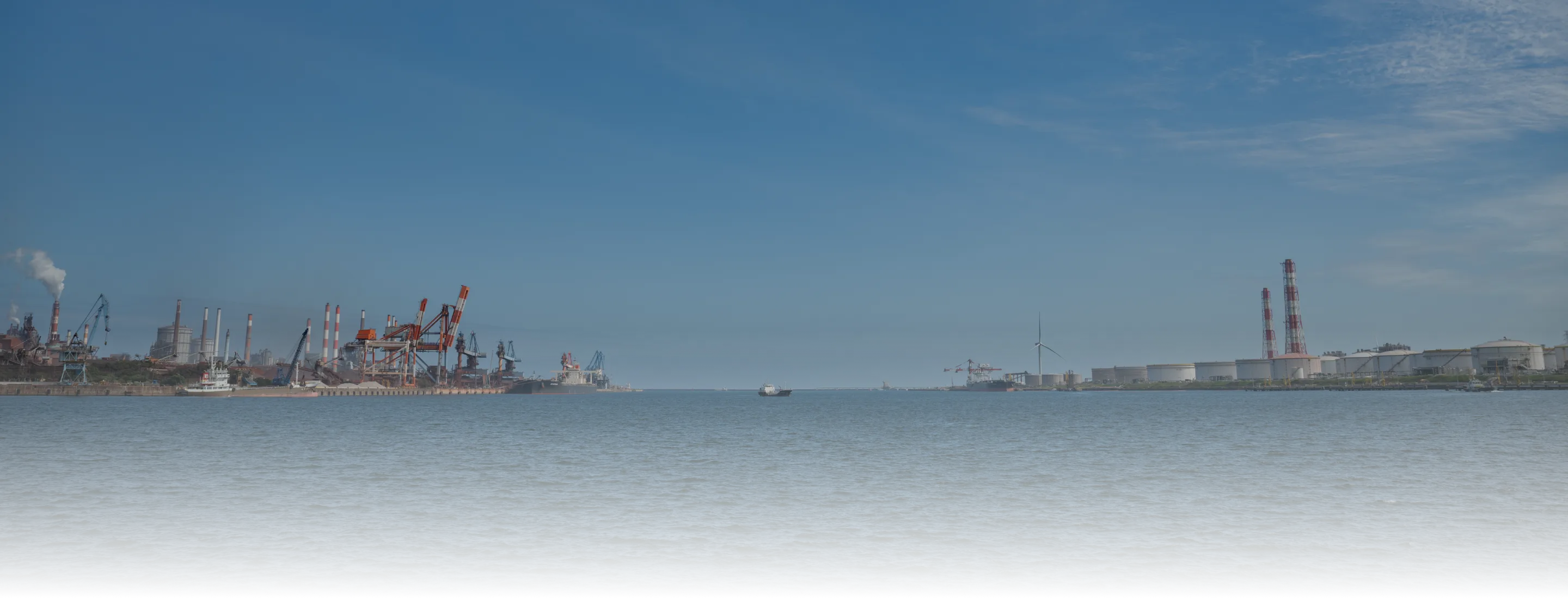 海沿いに工場や煙突が立ち並ぶ工業地帯の風景