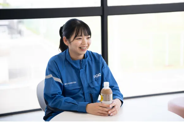 休憩スペースのテーブルに座る女性社員が飲み物を手に笑顔を見せ、リラックスして過ごしているひととき