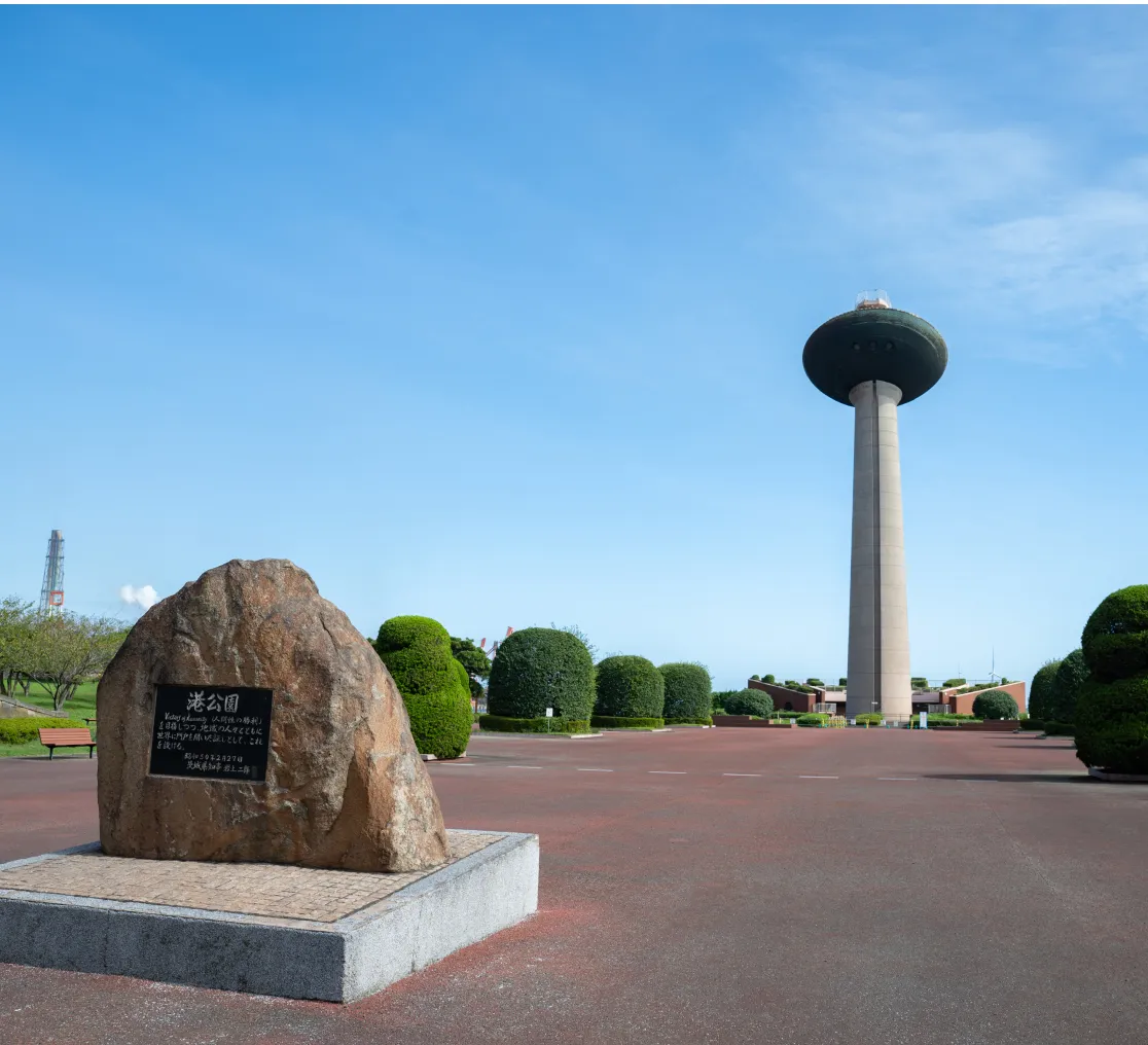 手前には記念碑の大きな石が置かれ、整えられた植木と広々とした広場が広がる
